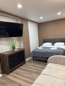 a bedroom with two beds and a flat screen tv at Sauna Dharma Stay Self check in in Telšiai