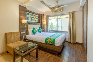 a bedroom with a bed and a window and a table at Treebo Aaram Orchard in Ahmedabad