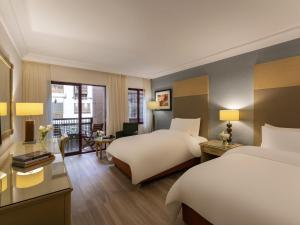 a hotel room with two beds and a desk at Mövenpick Resort Petra in Wadi Musa