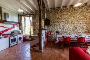 a kitchen with red chairs and a stone wall at La tour du guet in Arouille