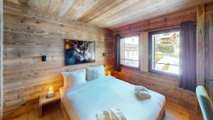 a bedroom with a wooden wall with a bed and a window at Chalet Dents Blanches - Latitude Champéry in Champéry +99 photos
