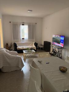 ein Wohnzimmer mit weißen Möbeln und einem Flachbildfernseher in der Unterkunft Catarinas in Chivilcoy