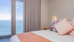 a bedroom with a bed with a view of the ocean at Pure Emotions Beach House in Knysna