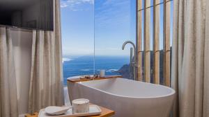 a bath tub in a bathroom with a large window at Pure Emotions Beach House in Knysna +44 photos