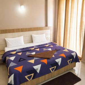a bedroom with a bed with a blue comforter at Vrindavan Viharini Kunj in Chhatikara
