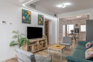a living room with a couch and a tv at Casa Parque Benavente Conil in Conil de la Frontera