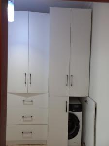 a white closet with white cabinets and a microwave at Flodril Appartment in Durrës