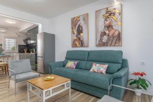 a living room with a blue couch and a kitchen at Casa Parque Benavente Conil in Conil de la Frontera