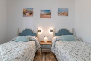 two beds sitting next to each other in a bedroom at Casa Parque Benavente Conil in Conil de la Frontera