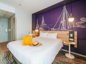 a hotel room with a large bed with a hat on it at ibis Styles Ancenis Centre in Ancenis +78 photos