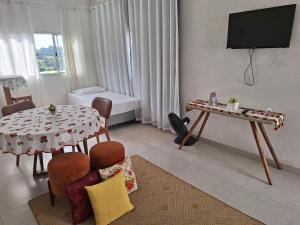 a living room with a table and a television at Pousada Dona Terezinha in Formiga