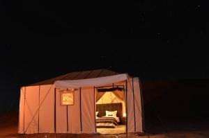 an orange tent with a bed in it at night at Camping nature in Jeradat