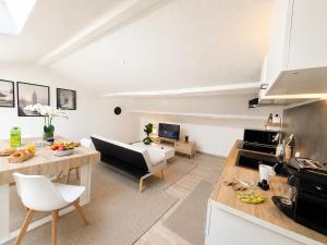 a kitchen and living room with a couch and a table at " L'Oratoire Mansardé " Linge fourni - Wifi - TV in Lagardelle-sur-Lèze