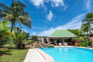 a pool at a resort with palm trees and a gazebo at Gites villa bagatelle piscine et Plage à 900m in Sainte-Rose