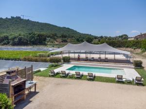 a swimming pool with a tent and chairs next to a river at Mas Tortós in Palafolls