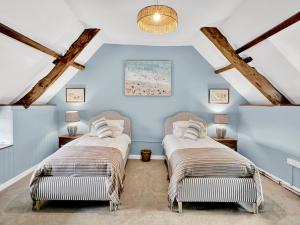 two beds in a room with blue walls and wooden beams at Bobs Cottage Porlock Weir in Porlock