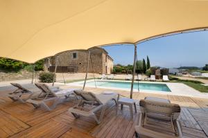 a patio with chairs and a large umbrella next to a pool at Mas Tortós in Palafolls