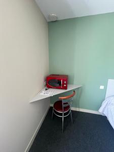 a room with a desk with a red radio on it at Hôtel des Voyageurs in Changé