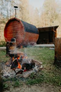 a fire pit in the grass with a boat in the background at Glamping Všímarský potok in Malšín