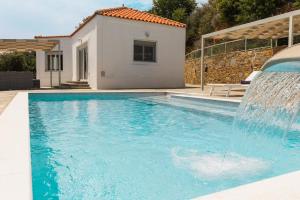 a swimming pool with a water fountain in front of a house at Villa Mirage Skopelos in Skopelos Town