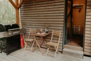 a patio with a table and chairs and a stove at Glamping Všímarský potok in Malšín