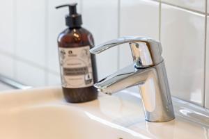 a sink with a soap dispenser next to a bathroom sink at Ferienwohnung Halde Hoheward in Recklinghausen +29 photos