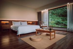 a bedroom with a bed and a chair and a table at Qingcheng Mountain Wujing Mountain Residence in Dujiangyan