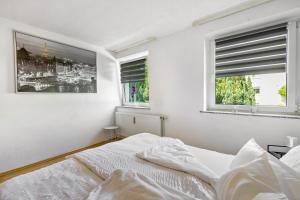 a white bedroom with a bed and two windows at Ferienwohnung Halde Hoheward in Recklinghausen