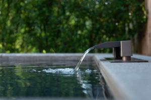 a water faucet pouring water into a swimming pool at Qingcheng Mountain Wujing Mountain Residence in Dujiangyan