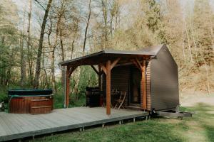 a small cabin with a deck and a grill at Glamping Všímarský potok in Malšín