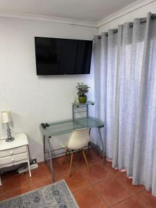 a table with a chair and a television on a wall at Protea Hoogte Flatlet in Brackenfell