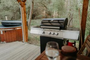 a grill on a deck with a glass of wine at Glamping Všímarský potok in Malšín +29 photos