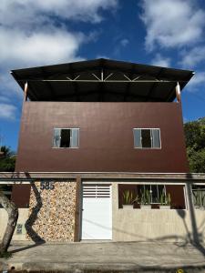a brown house with a white garage at Shiva Hostel in Rio das Ostras