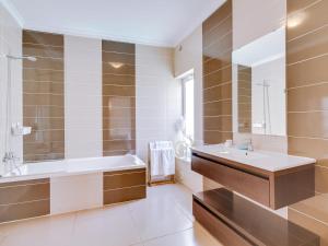 a bathroom with a tub and a sink and a bath tubermott at Villa Monica with Private Pool and Jacuzzi in Quarteira +20 photos