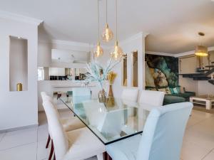 a dining room with a glass table and white chairs at Villa Monica with Private Pool and Jacuzzi in Quarteira