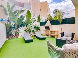 a patio with green grass and chairs and a fireplace at Villa Monica with Private Pool and Jacuzzi in Quarteira