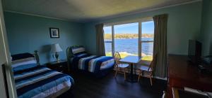 a bedroom with two beds and a view of the water at St Ann's Motel & Cottage in Baddeck