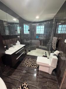 a bathroom with a shower and a toilet and a sink at Elysium Noire in Spanish Town +24 photos