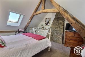 a bedroom with a bed and a stone wall at Le parfum des fleurs in Plussulien