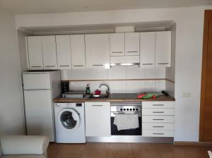 a kitchen with white cabinets and a washing machine at Apartamento rodeado de mar y montañ in El Verger