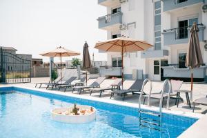 a swimming pool with chairs and umbrellas on a building at Lux Ariana in Donji Štoj
