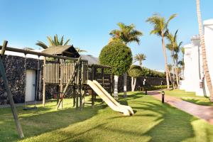 a playground with a slide in the grass at Plus Fariones Apartamentos in Puerto del Carmen