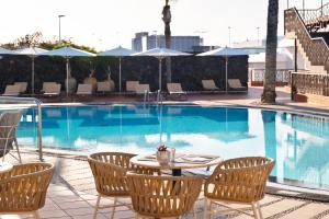 a swimming pool with a table and chairs next to it at Plus Fariones Apartamentos in Puerto del Carmen
