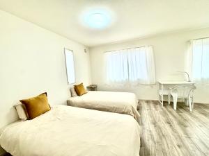 two beds in a white room with a table at Villa 勝浦 in Katsuura