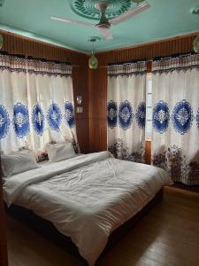 a bed in a bedroom with blue and white curtains at Giggle in Srinagar