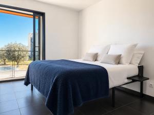 a bedroom with a bed with a blue blanket and a window at Sea Road Perpignan in Perpignan
