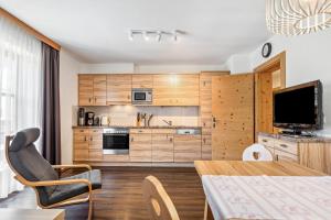 a kitchen with wooden cabinets and a table and a television at Appartements Stockinger B4 in Grossarl