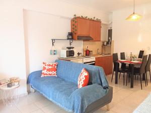 a living room with a blue couch and a kitchen at Kyma studio Modern Stay in Nea Artaki