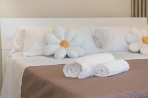 a bed with two rolled towels and a flower on it at VJ Apartment in Giardini Naxos
