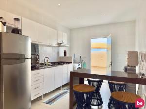 a kitchen with a refrigerator and a table with stools at Boas Vistas - Canoa Quebrada in Canoa Quebrada